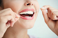 Frau putzt sich die Zahnzwischenräume mit Zahnseide