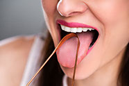 Frau streckt die Zunge raus und reinigt sie mit einem Zungenschaber